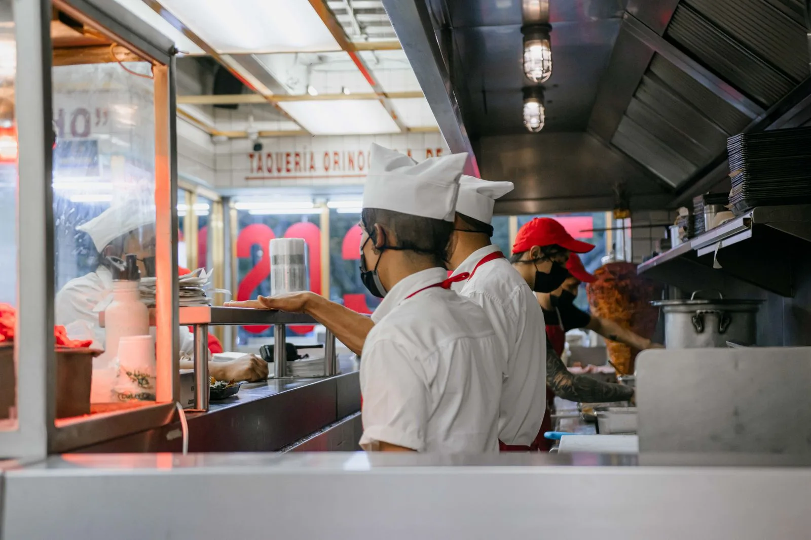 Kitchen staff preparing food to go at a taqueria counter