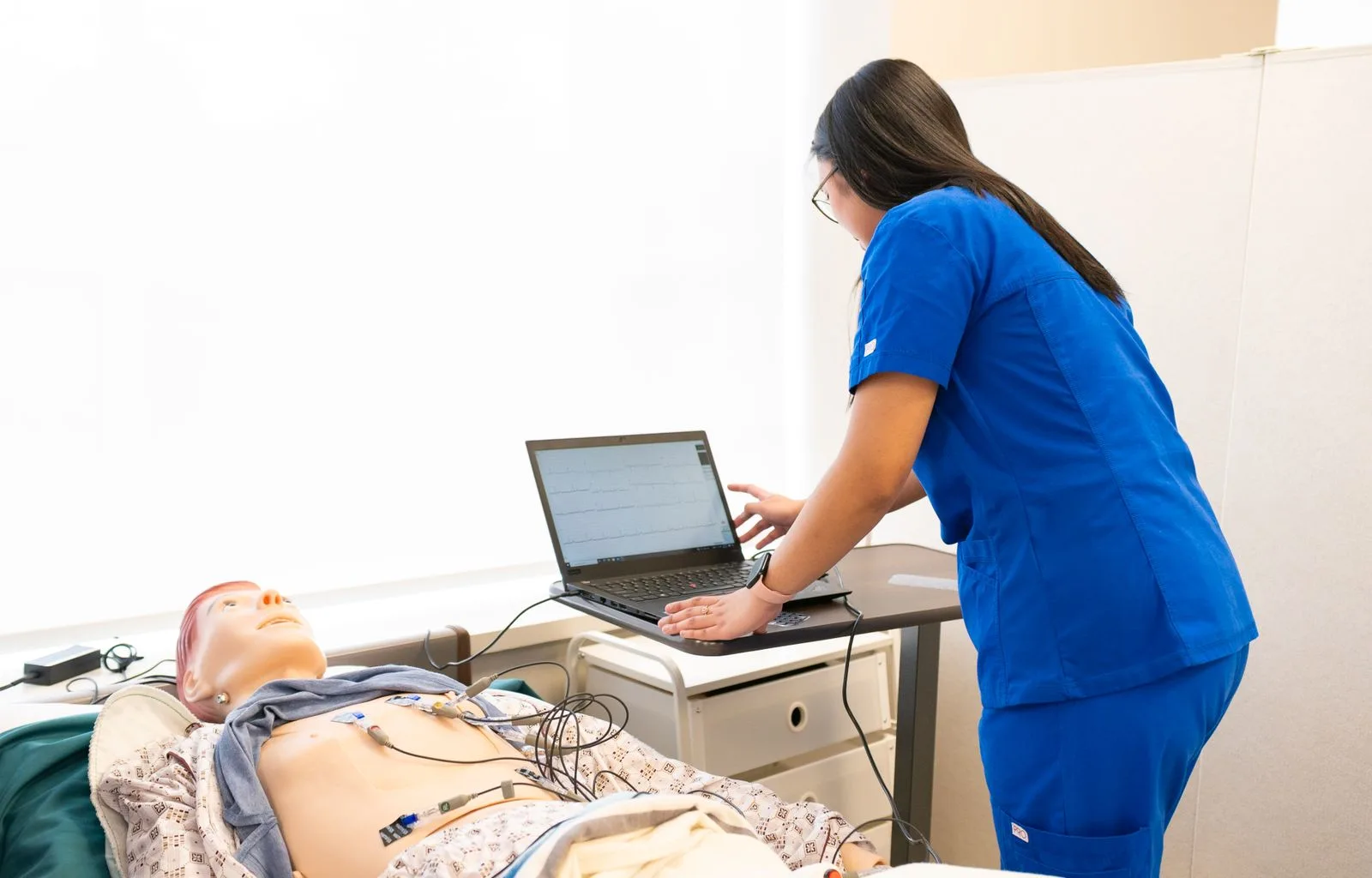 A nurse trainee working with a medical dummy in a simulation lab